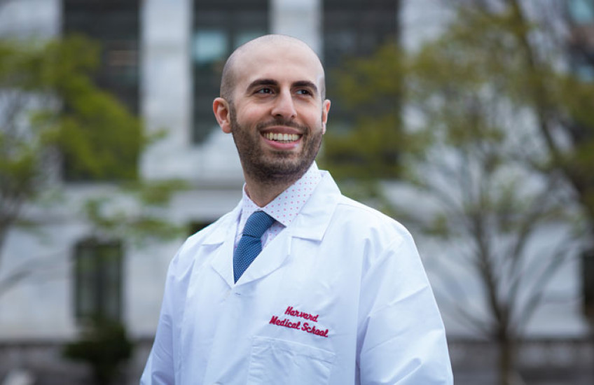 Headshot of Meshkin wearing a white coat with HMS logo with Quad behind him