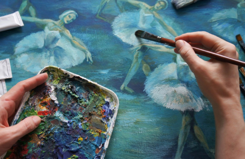 Close-up of a painter's hands working on a picture of dancers.