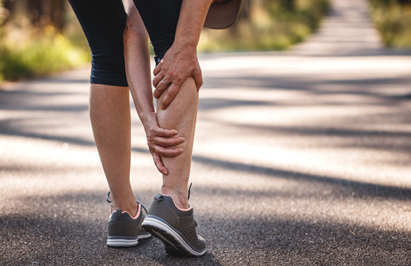 Person grasping lower leg in pain