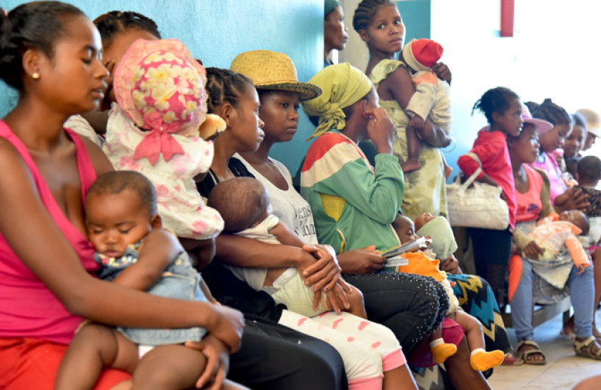 Women and children sitting and standing in a waiting room.
