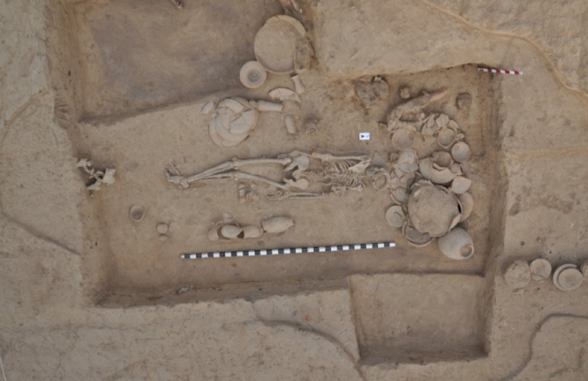 Photo of gravesite taken from above shows a skeleton and pots with a measuring stick