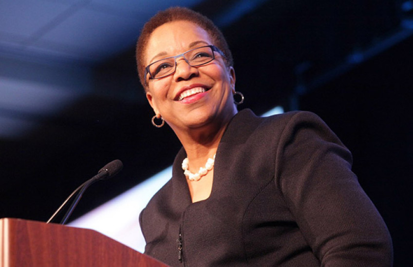 Joan Reede standing behind a podium, smiling