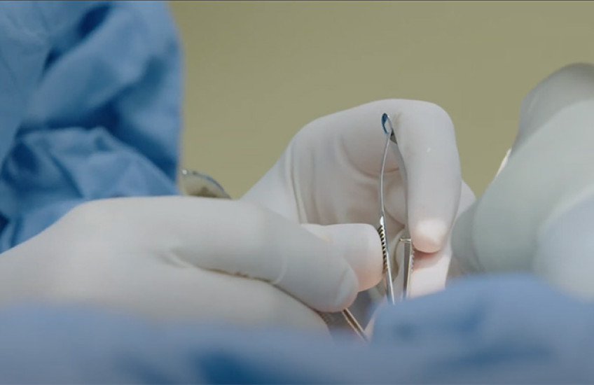 surgeon's hands holding implements