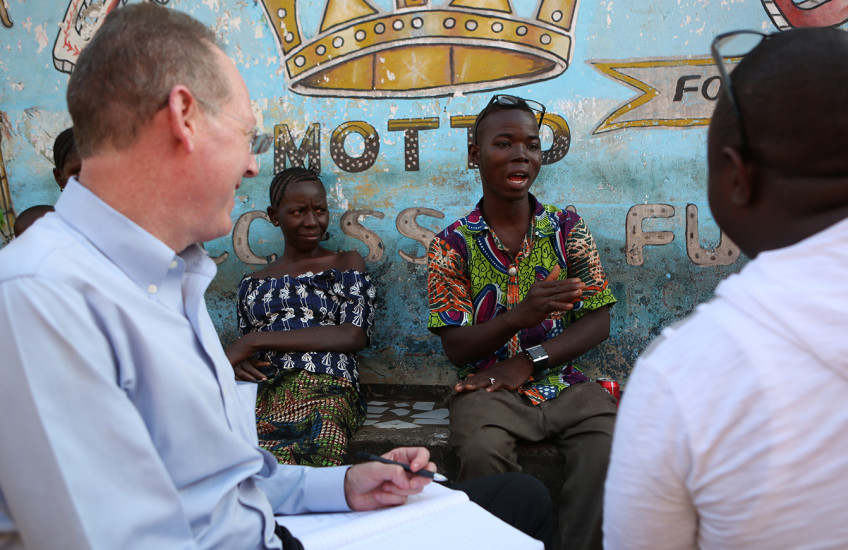 Four people having a conversation sit in front of a colorful mural