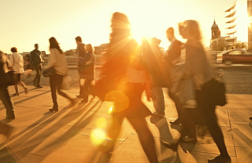 Motion blurred photo of people walking backlit by the sun.
