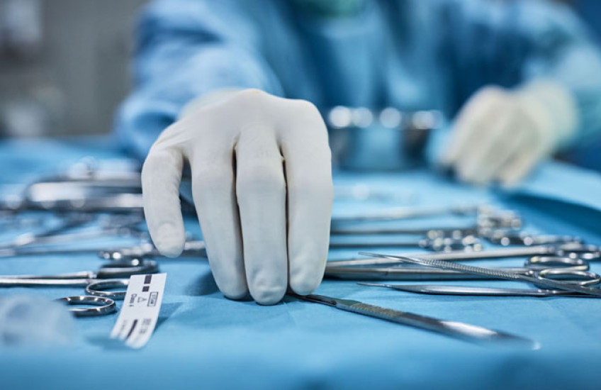 Hands reaching for surgical tools.