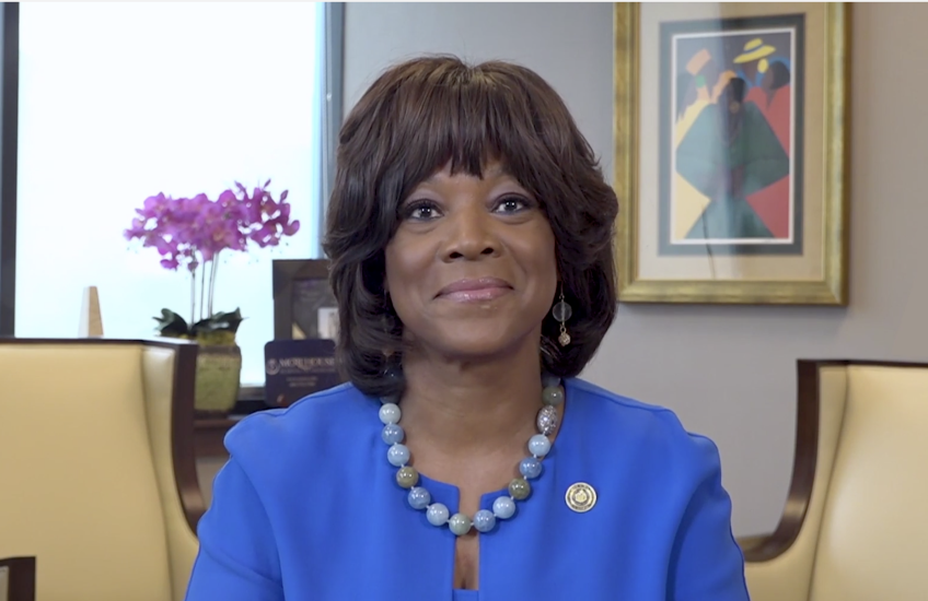 Image of Dr. Rice, wearing a blue suit, seated at a desk in her office