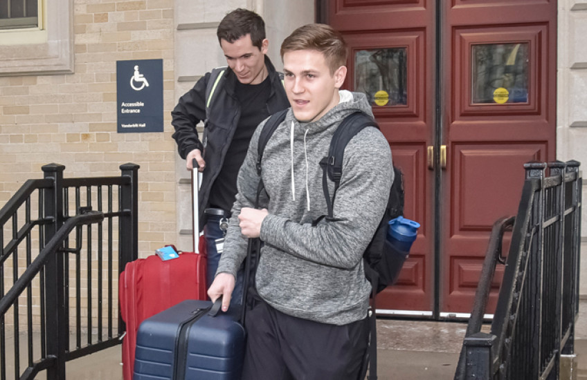 photo of two male students carrying luggage down stairs in front of Vanderbilt Hall