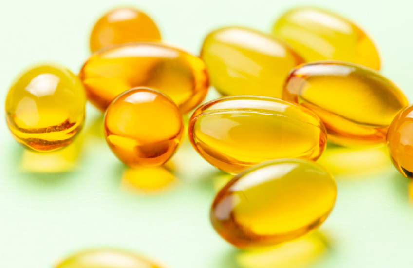 photo of vitamin D capsules on a light green background