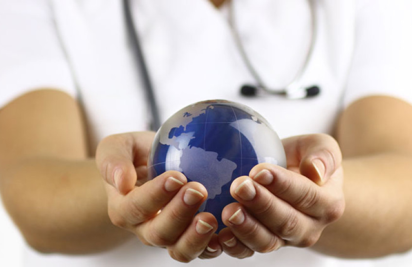 Stock image of white coated person holding a small earth globe