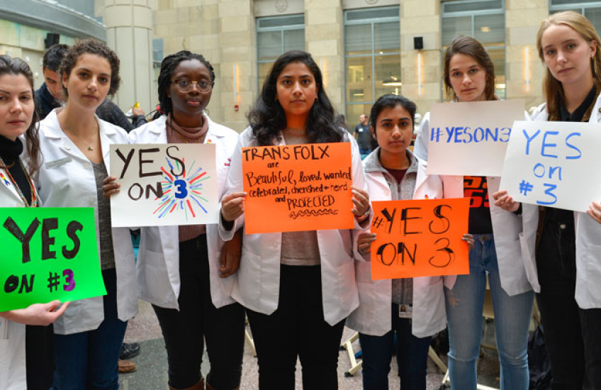 HMS students in white coats holding rally posters