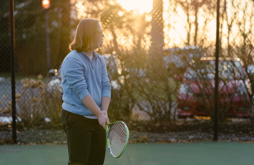 Silhouette of a male teen with Down syndrome holding a tennis racket