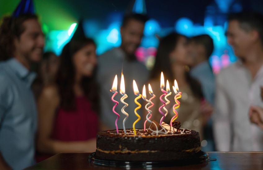 Close-up on a candle-lit cake on a table at a birthday party 