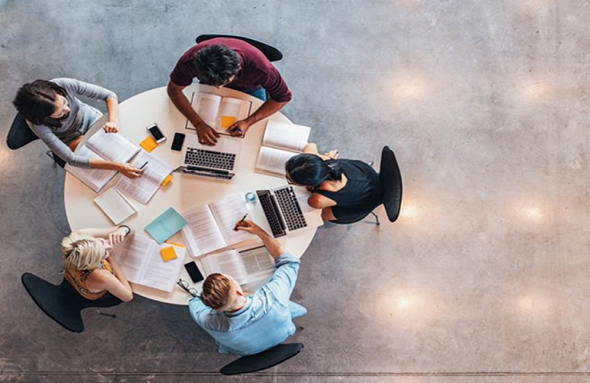 Photo of a study group at a table with computers, books, and notes