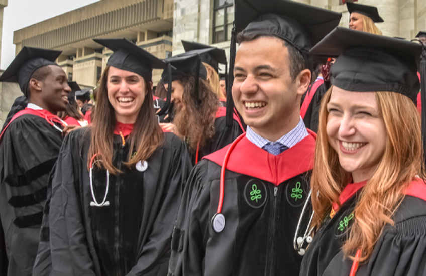 Smiling group of graduates on the steps of the Quad
