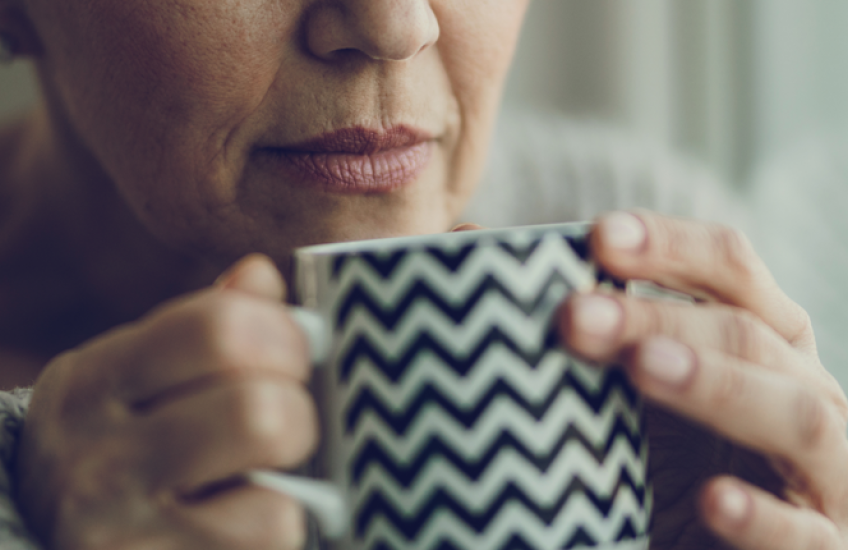 close up of older woman holding coffee mug to her nose