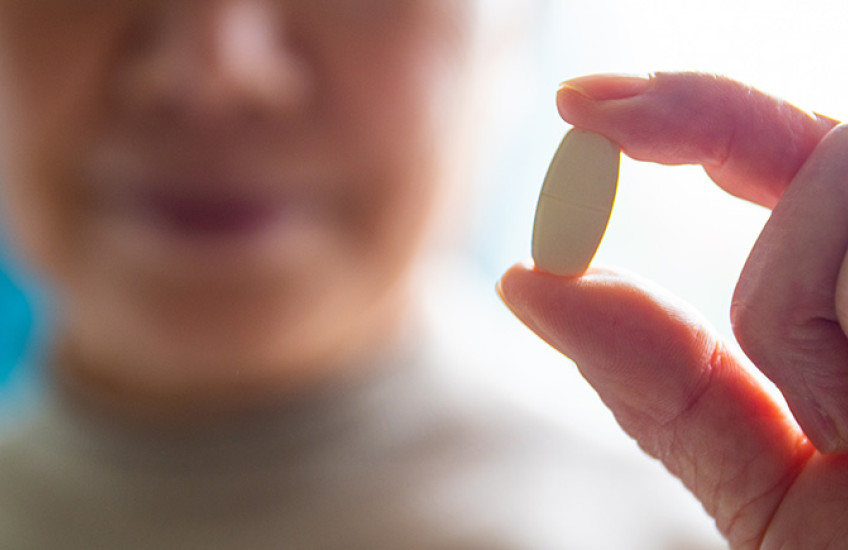 blurred face of senior women showing a pill