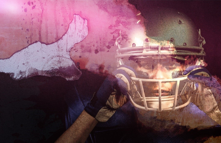 A headshot of a football player gripping their helmet 