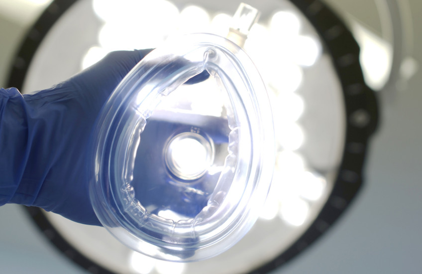 anesthetic mask held toward camera as if being put on the viewer