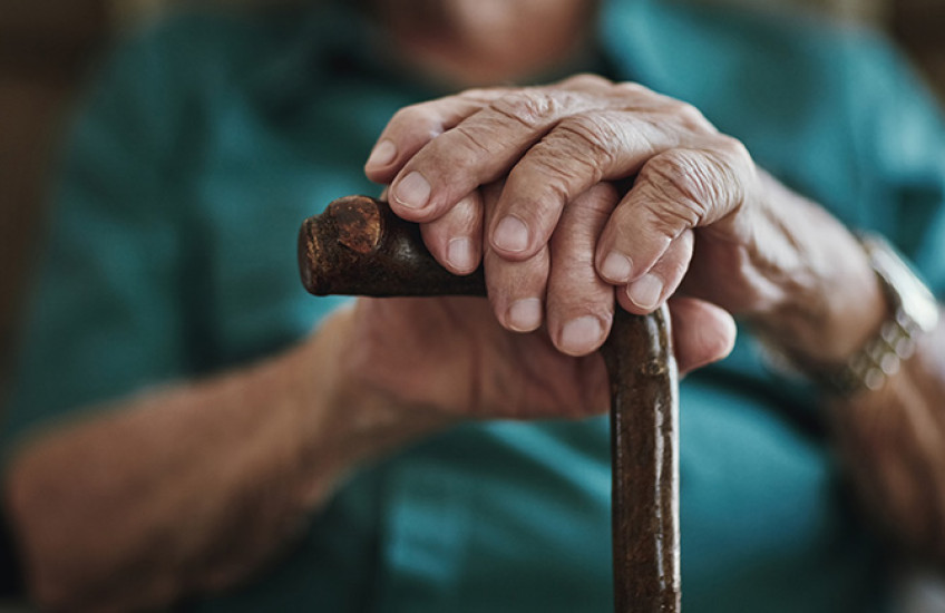 close up photo of a senior man's hands on a cane