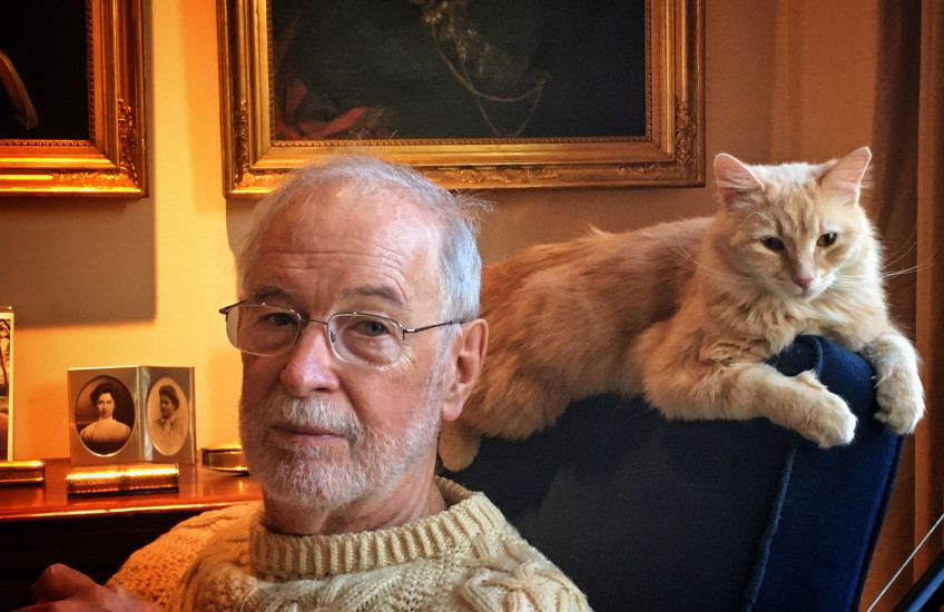 professor in sweater with cat on armchair