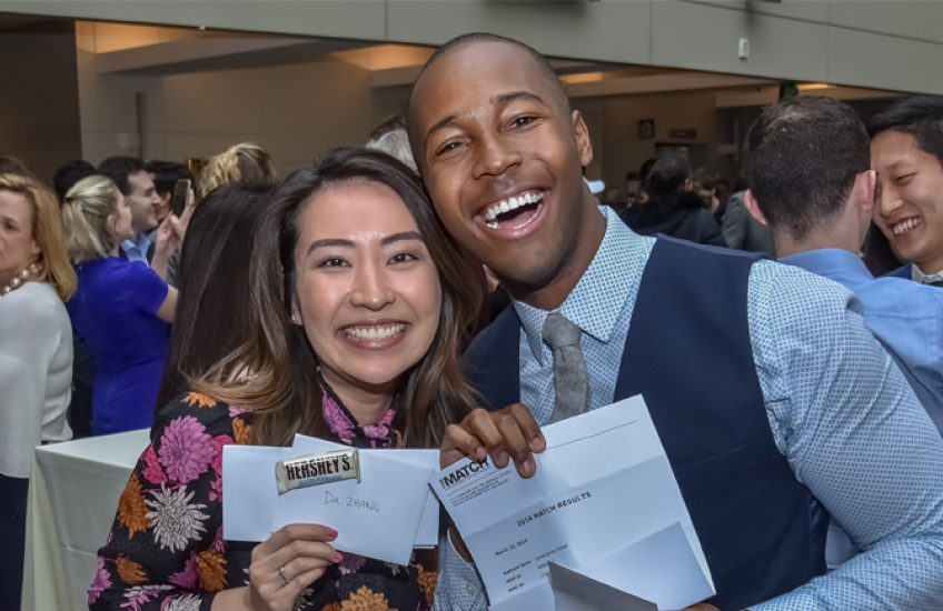 Two HMS Students proudly holding up their Match Day letters.