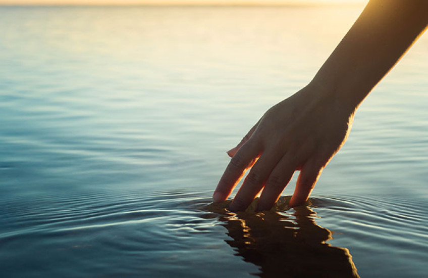 Photo of hand touching a pool of water