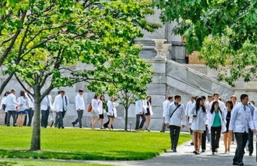 Students in white coats walk on the quad