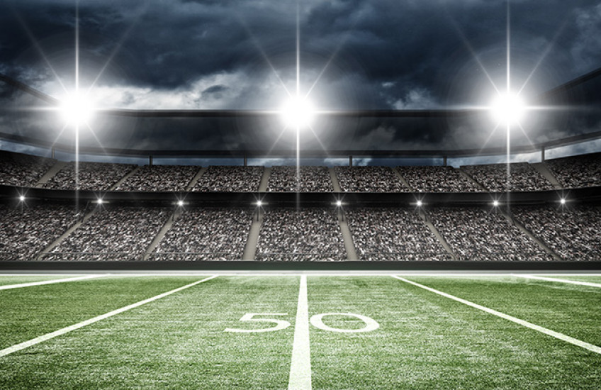 football stadium showing 50 yard line, crowd in seats and lights