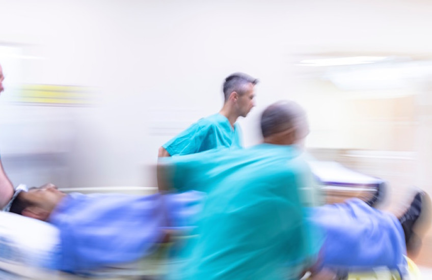 Medical staff hurry through a hospital with a patient on a gurney.