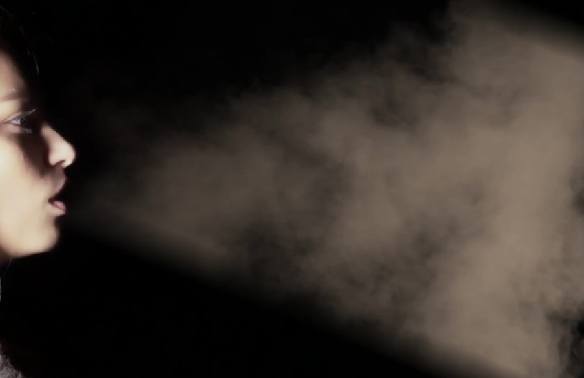 A girl blows smoke