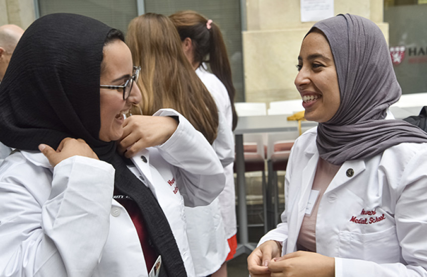 Two HMS students in Class of 2023 chat with white coats on.