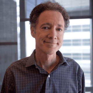 Portrait photo of Bruce Yankner in an office with window shades partially lowered