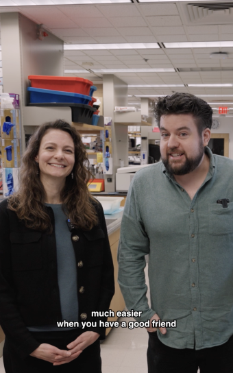 Ruth Franklin and Ruaidhrí Jackson smile at the camera in their shared lab space