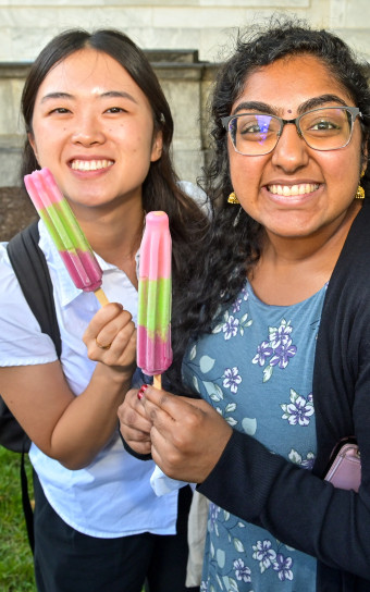 Two students hold colorful ice pops on the Quad