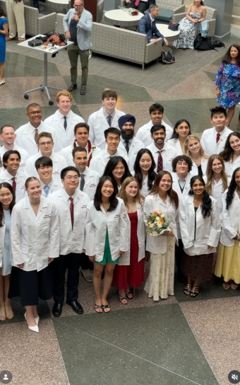 A cluster of students in the Class of 2030 pose in their new white coats