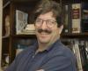 Head shot of a smiling man in front of a bookcase