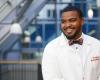smiling young man in a bow tie and HMS white coat
