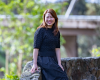 A woman sits on a stone wall and smiles at the camera