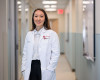 A woman in an HMS/Joslin white coat stands in a hallway.
