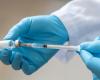 Blue-gloved hands holding a vaccine syringe