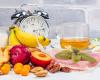 Photo of a bunch of fruit and food with an alarm clock nearby