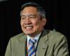 Photo of Bernard Chang with a green suit jacket and striped tie, smiling.