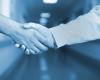 Photo illustration of two health care providers shaking hands in hospital hallway