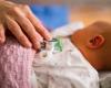 Photo of a hand with a stethoscope on a newborn baby's chest 