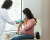 A doctor prepares a pregnant person's arm for a vaccine