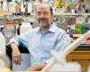 A photo of Greenberg sitting in his lab and leaning on a lab bench, surrounded by lab supplies