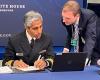 Murthy in uniform seated at table looking at laptop with Beckman to right leaning in; a backdrop behind them reads The White House