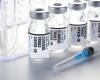 vials labeled "clinical trials COVID 19" in front of test tube rack, with syringe in foreground