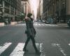 A woman in a surgical mask crossing a street in mid-town Manhattan